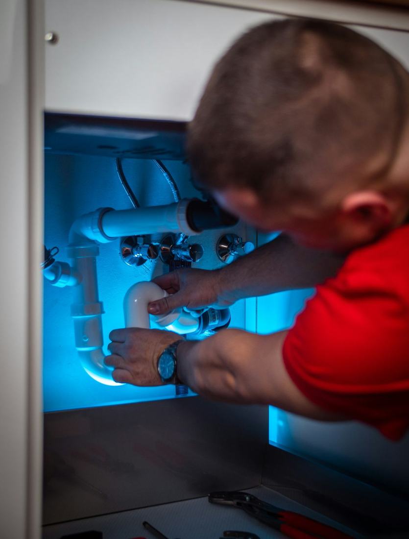 Plumber working on a drain under a sink