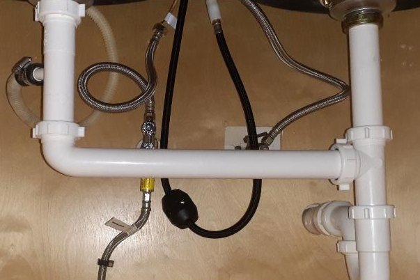 New white drain pipes and supply lines under the same sink