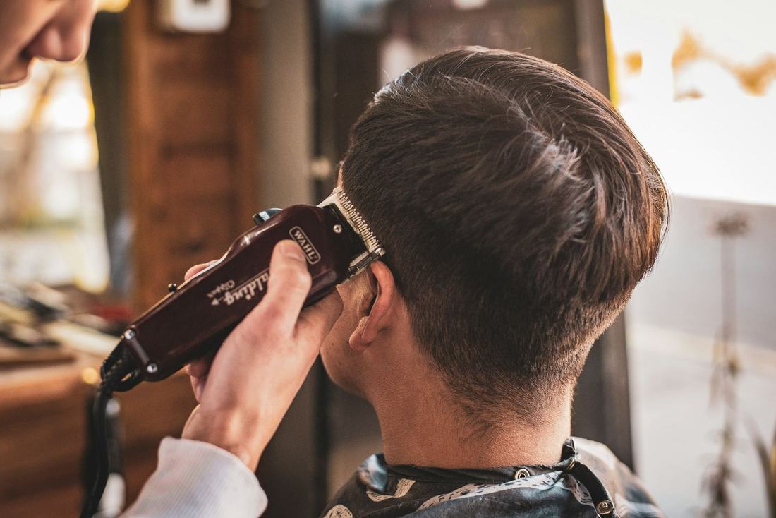Barber trimming the back of a client's hair with clippers