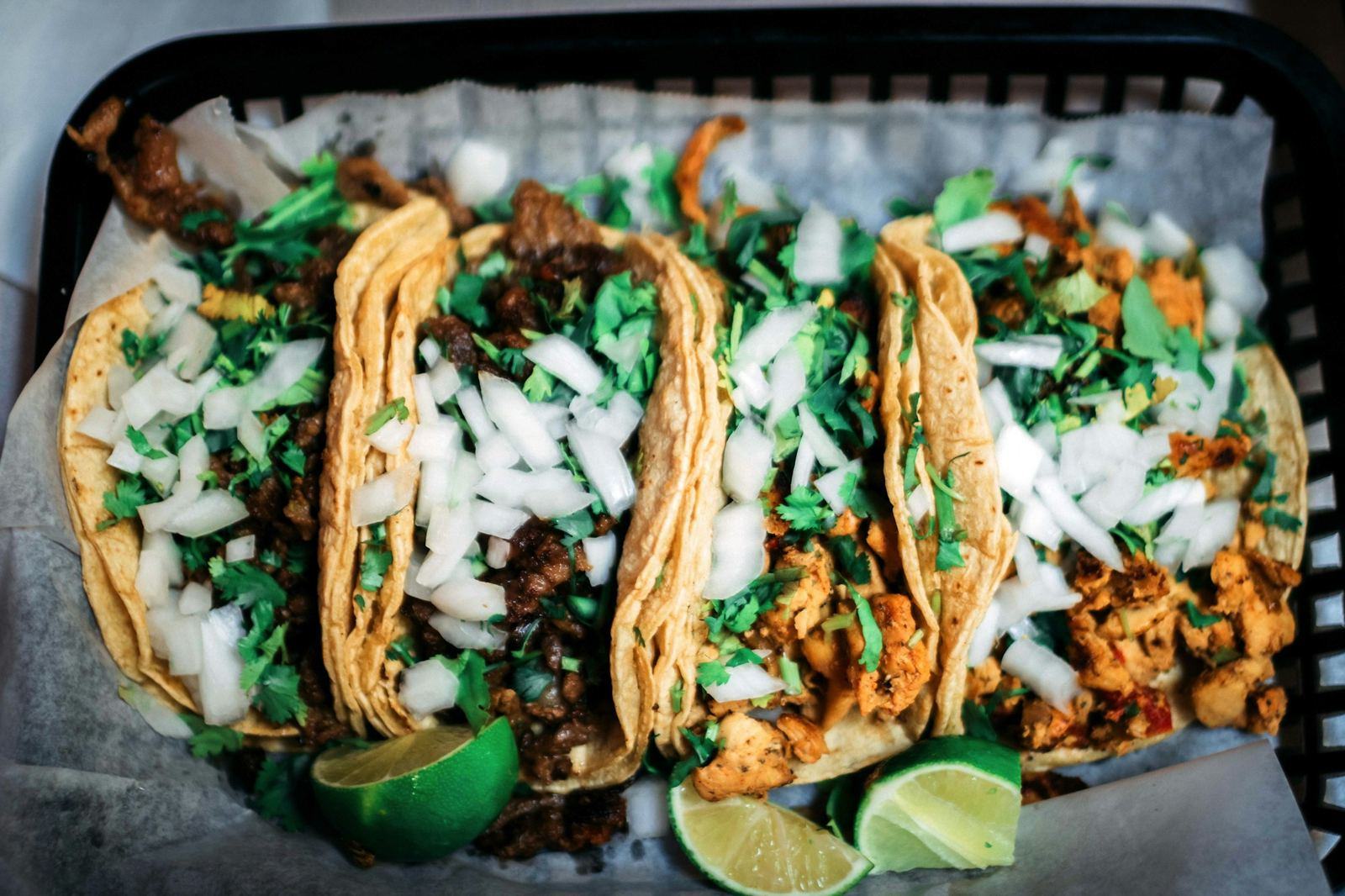 Tray of street tacos with cilantro, onion and lime