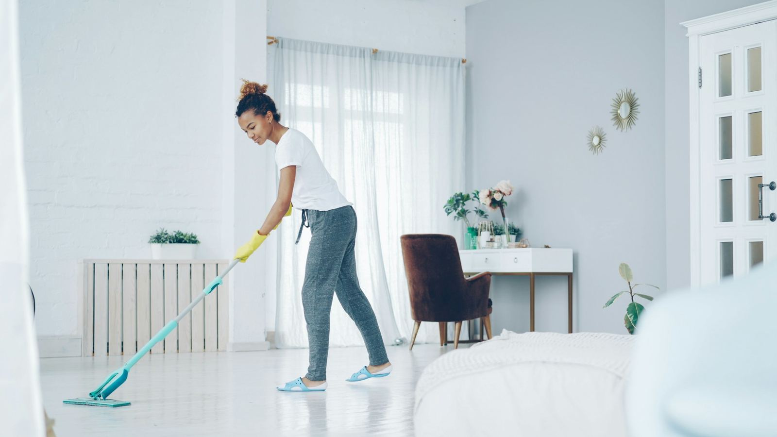 Cleaner mopping the floor of a bright living room